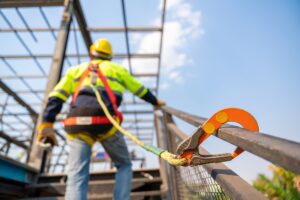 A construction worker working at height, Construction workers are working on steel roof trusses with Fall arrestor device for worker with hooks for safety body harness on the construction site.