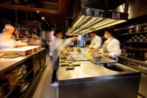 Hectic cooks working in a busy commercial kitchen at a restaurant - food and drink establishment concepts
