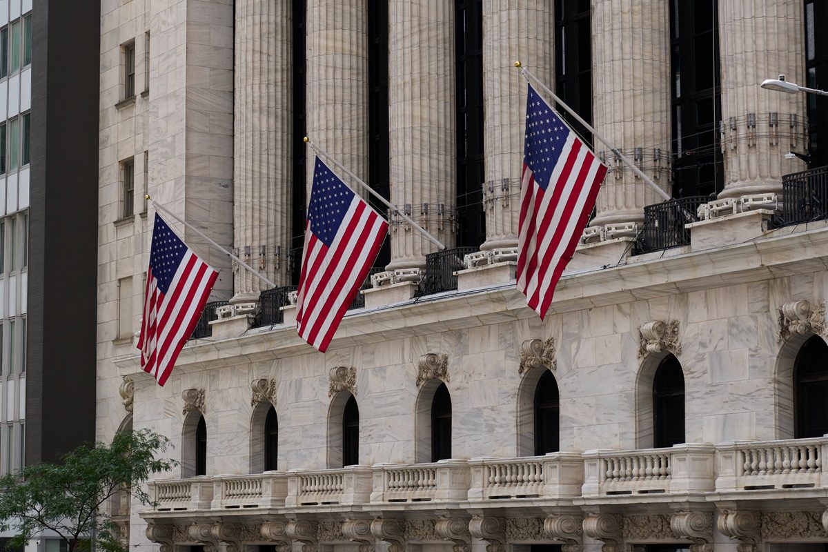 Four american flags are waving on the facade of a classic building in new york city