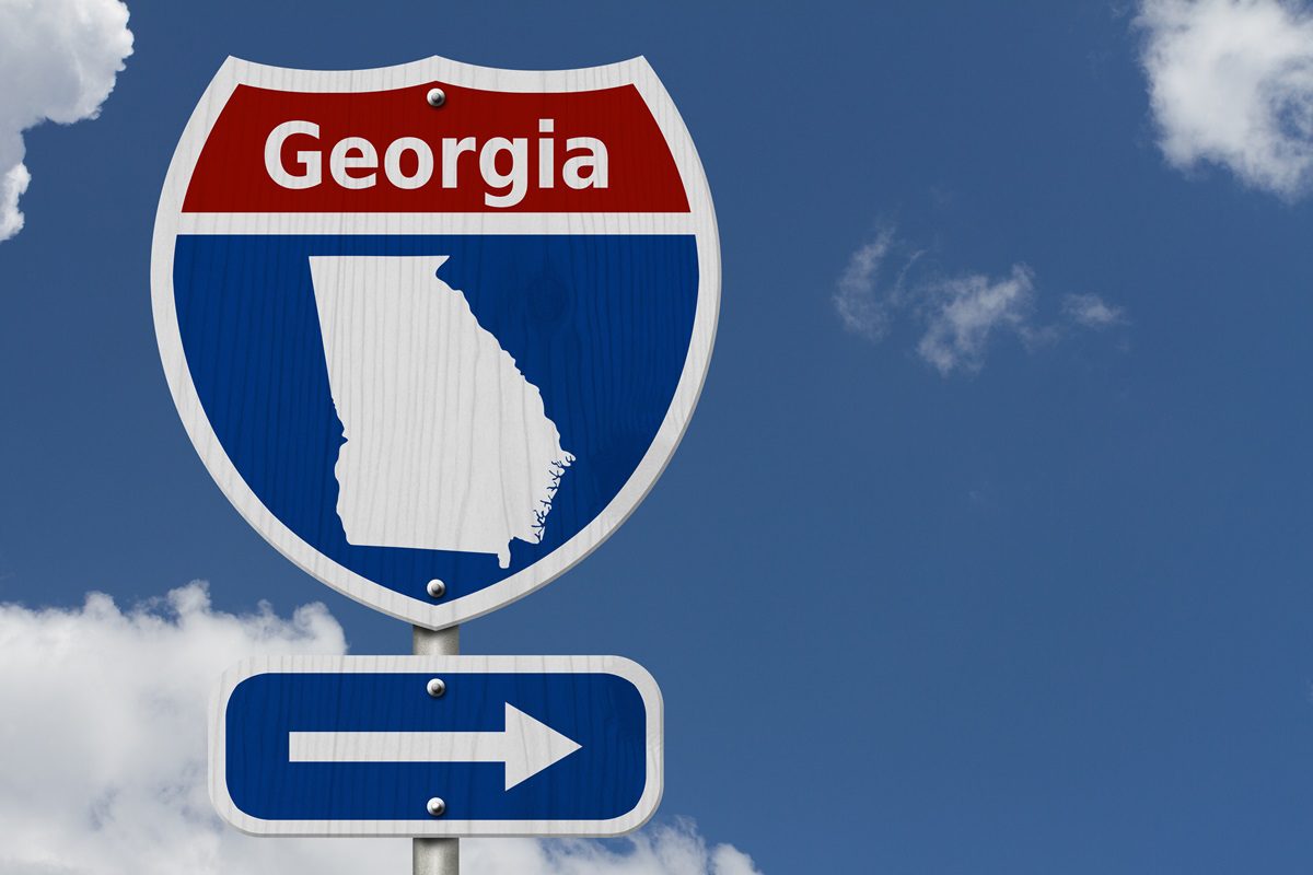 Road trip to Georgia, Red, white and blue interstate highway road sign with word Georgia and map of Georgia with sky background