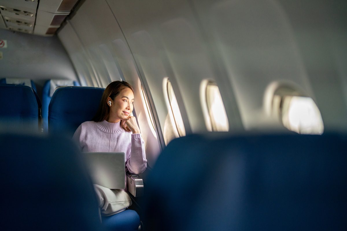 A successful businesswoman passenger relaxes and enjoys the scenic view outside the window as she travels on a flight
