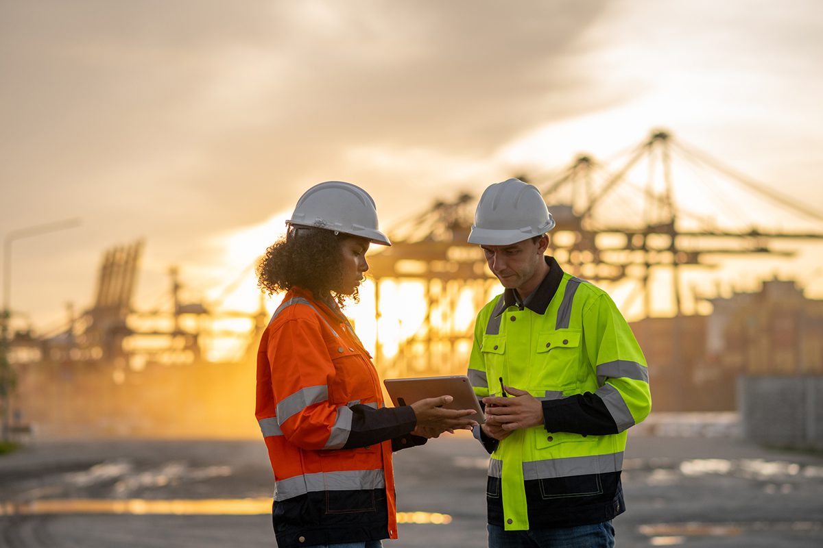 Dock workers review inventory and logistics data on a tablet.