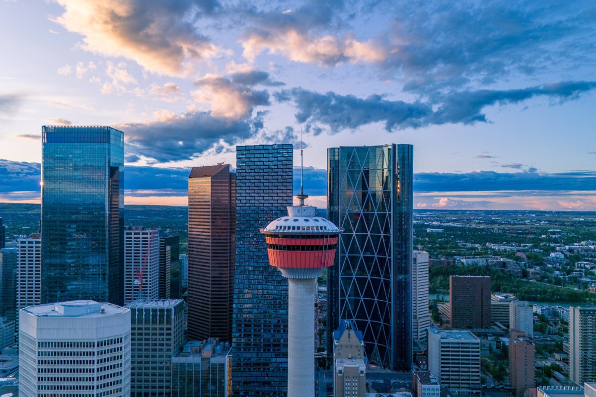 A breathtaking aerial image of Calgary’s downtown skyline captured at golden hour. The warm sunset light reflects off the glass facades of the skyscrapers, creating a stunning contrast with the evening sky. Perfect for real estate, tourism campaigns, and cinematic cityscape features.