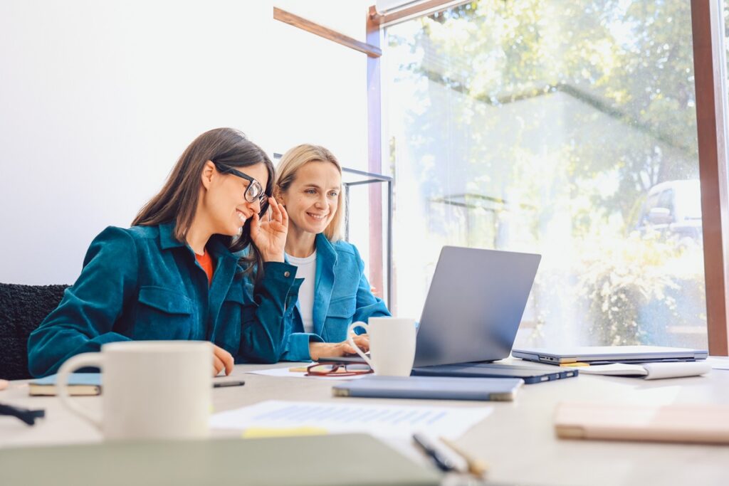 Female office staff discuss work-related issues in the workplace.