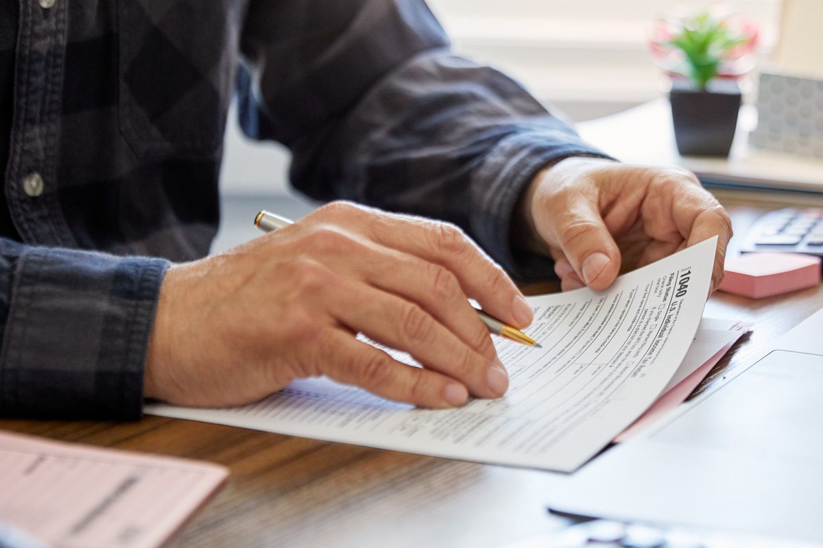 Close-up of a man holding a tax form, working from home