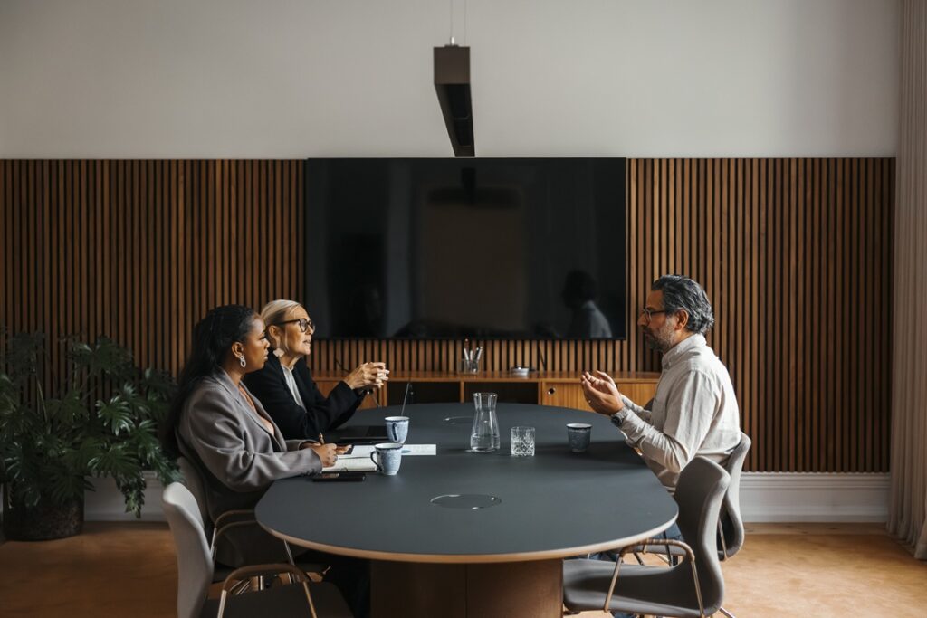 Businesswomen talking with man during job interview while sitting at table in office