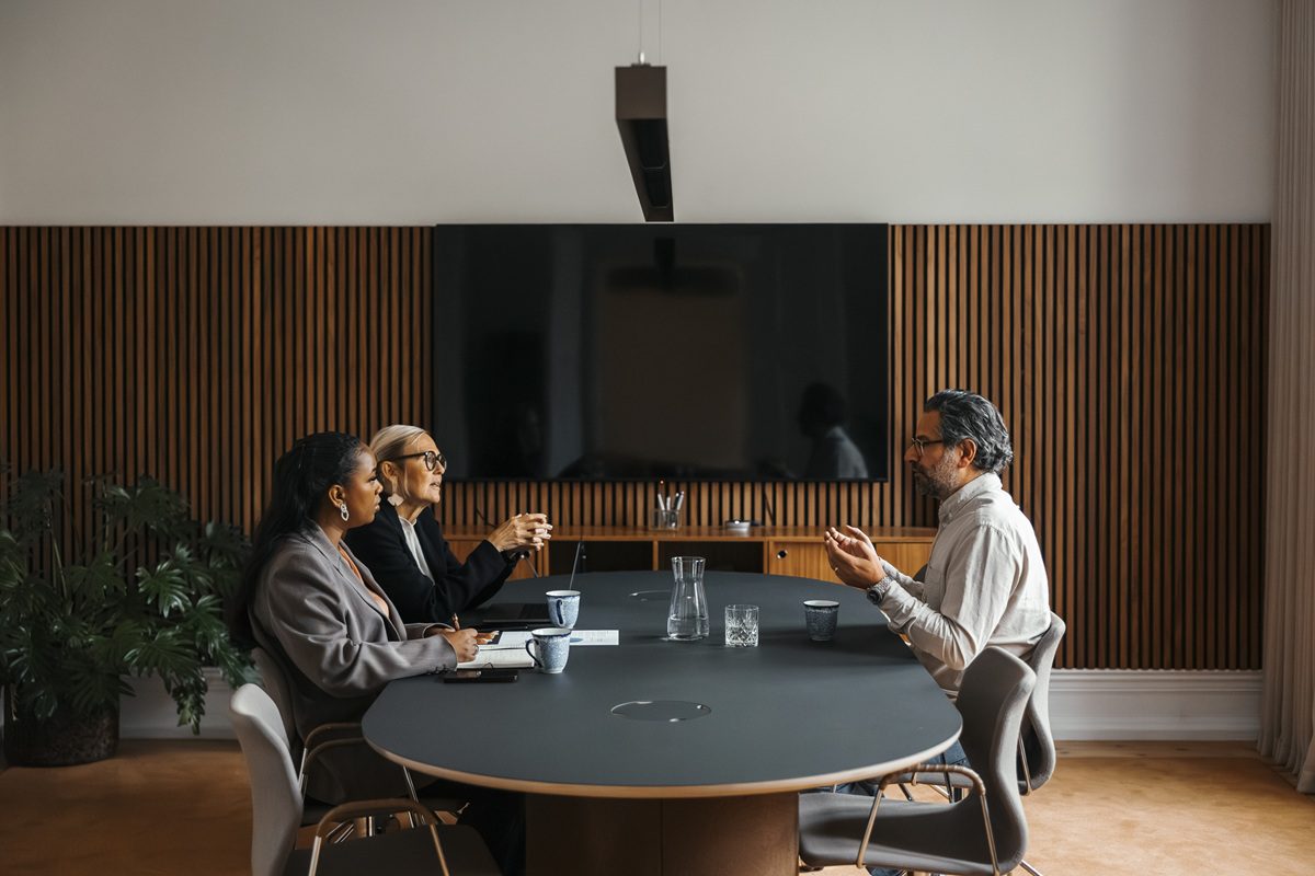 Businesswomen talking with man during job interview while sitting at table in office