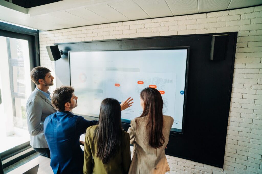 Professional colleagues collaborating at interactive screen in modern office