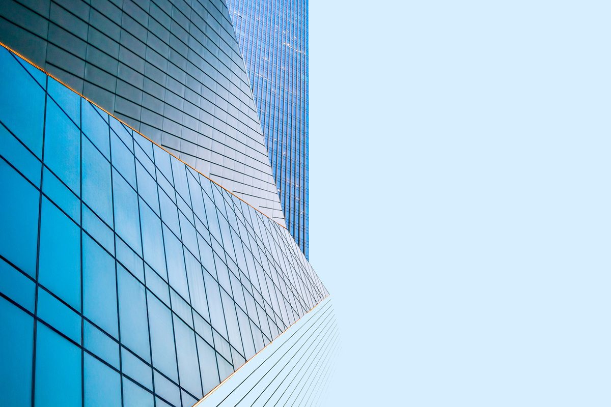 Modern glass skyscraper building reflecting blue sky