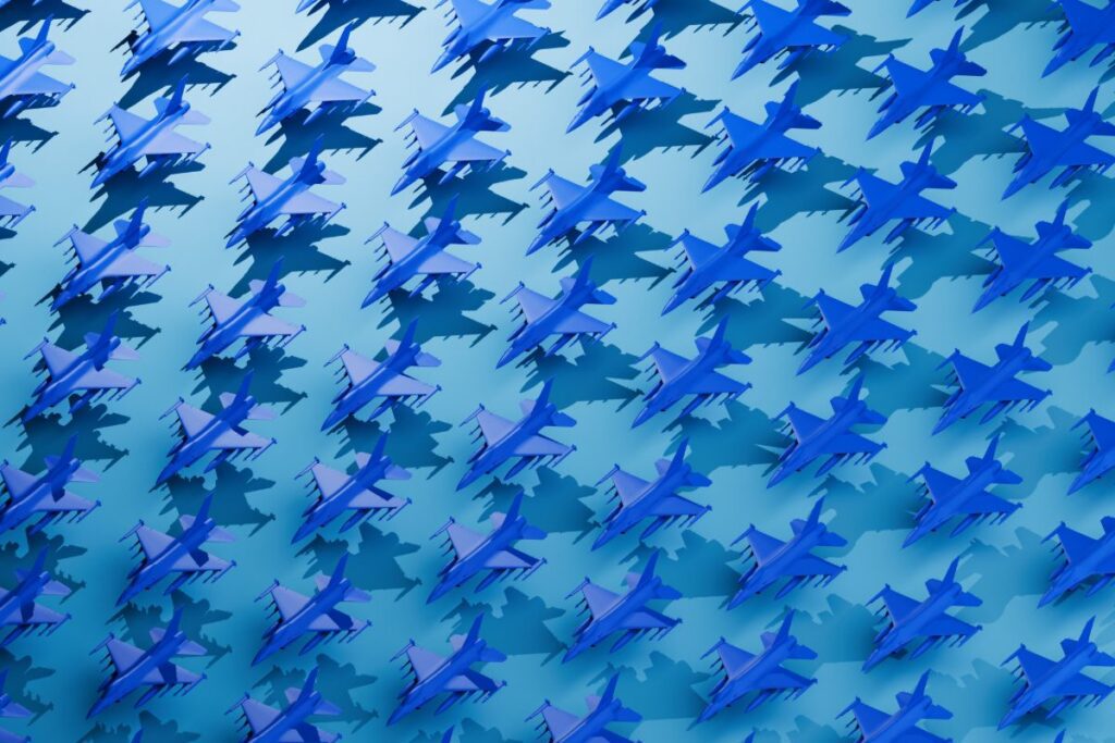 A conceptual image featuring a clean, evenly spaced grid pattern filled with stylized, block-colored fighter planes in bold blue tones. The visual evokes themes of coordination, power, and aerial strategy, with the repeated plane shapes suggesting organized force, tactical readiness, or mass deployment. The minimalist grid composition highlights ideas of control, uniformity, and calculated strength&mdash;ideal for visuals related to military strategy, air dominance, defense technology, or abstract representations of power and precision.