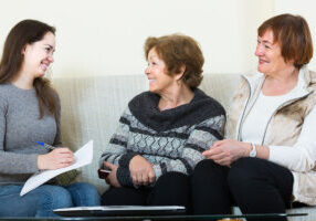 happy account manager helping elderly women with finances at home