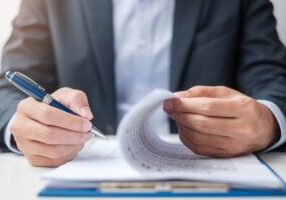 Businessman signing on contract documents after reading, man holding pen and approve on business report. Contract agreement, partnership and deal concepts - stock photo