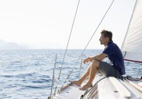 man sitting on bow of sailing yacht