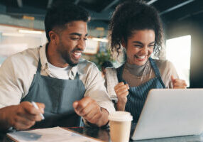 Laptop, team and success with people in cafe for product inventory, supplier deal and budget profit. Menu discounts, reputation rating and small business owner with employee in coffee shop for winner - stock photo