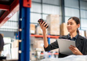 Warehouse manager with scanner making review of goods in warehouse for check the quantity and prepare data for send to warehouse management. - stock photo