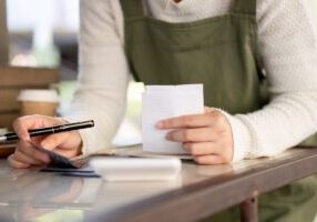A cropped shot of a female small business owner calculating her monthly expenses, checking bills receipts, managing her shop budget. people and financial concepts