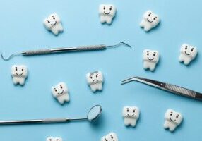 White tooth with caries on blue background and dentist tools mirror, hook