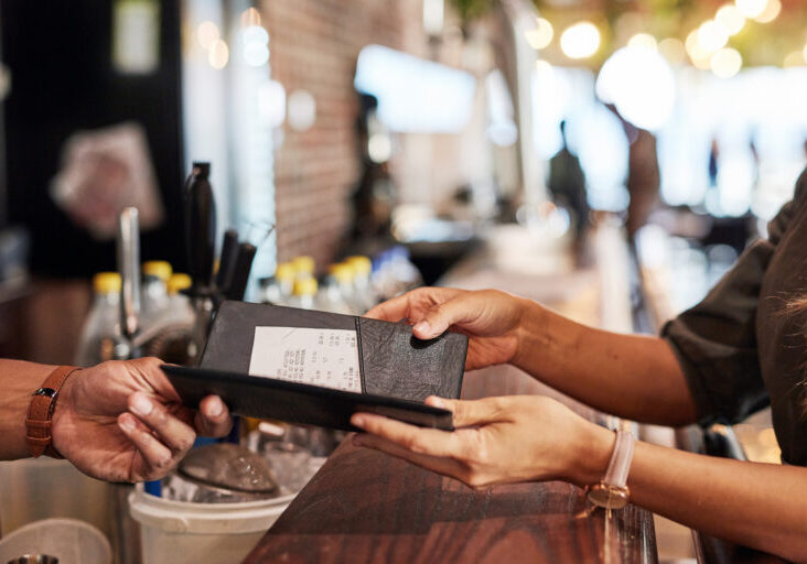Hands with bill, food service and people in restaurant, customer with receipt and payment with cashier or waiter. Fine dining, dinner and check at cafe, catering and hospitality with finance
