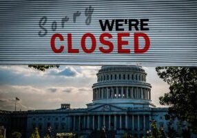 United States Capitol Building with a Old grunge steel metal roller shutter door with Sorry we're closed text.