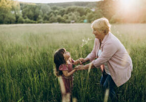 Grandmother and her little granddaughter walking in the field