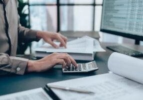 Investors working on desk office and using a calculator to calculate balance, profit, currency and cost. Accounting and Financial concept. - stock photo