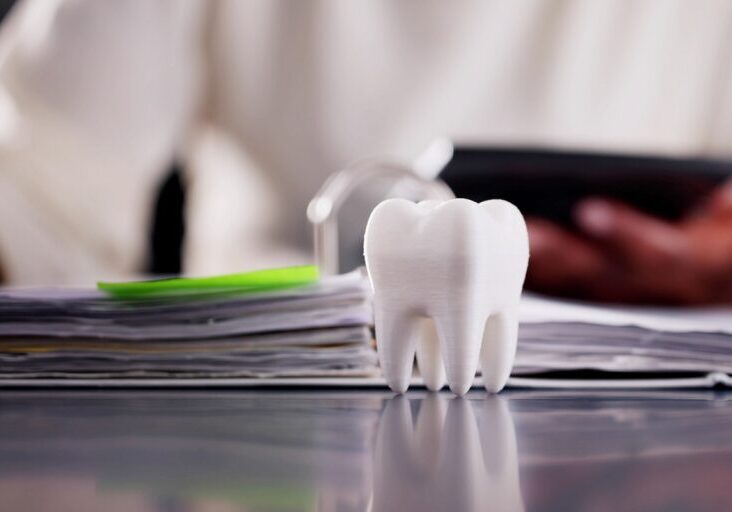 Dental Insurance Advisor Examining Bill for Tooth Implant on Office Desk, Saving Money with Budgeting - stock photo