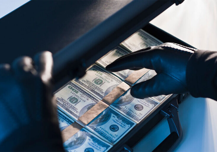 Money in a briefcase with gloved hands - stock photo