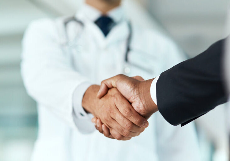 Cropped shot of a doctor shaking hands with a businessman in a hospital
