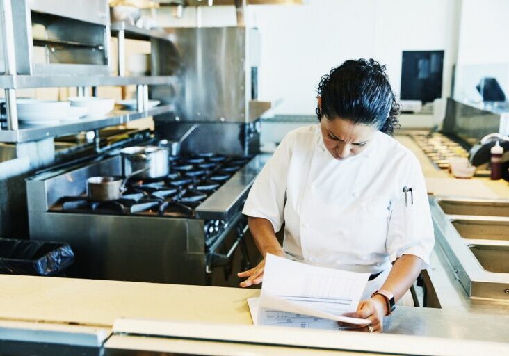 Female chef reviewing paperwork in restaurant kitchen