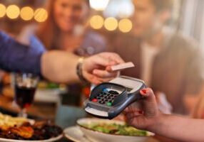 Group Of Friends Paying For Meal In Restaurant