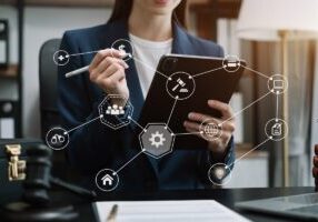 Judge in a courtroom using laptop and tablet with AML anti money laundering icon on virtual screen.