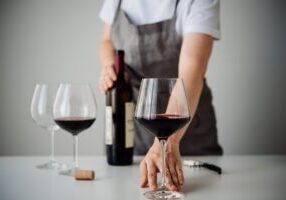 A bartender or sommelier pouring red wine in a glass. Wine tasting in a bar or restaurant.