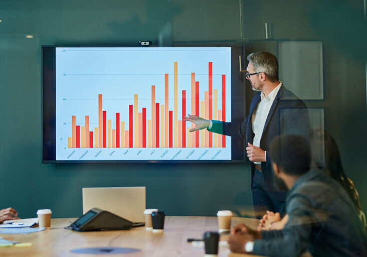 Businessman giving presentation to colleagues in boardroom - stock photo