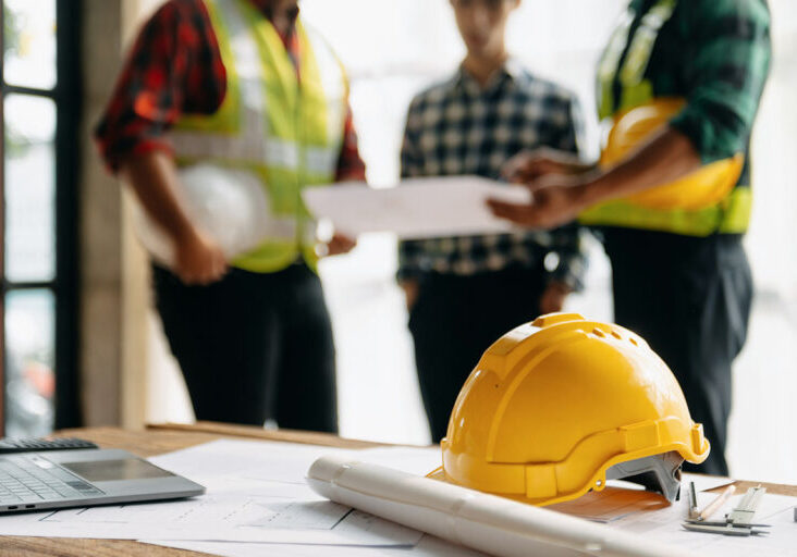 Engineer teams meeting working together wear worker helmets hardhat on construction site in modern city