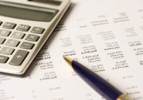 Calculator and pen on stack of financial documents