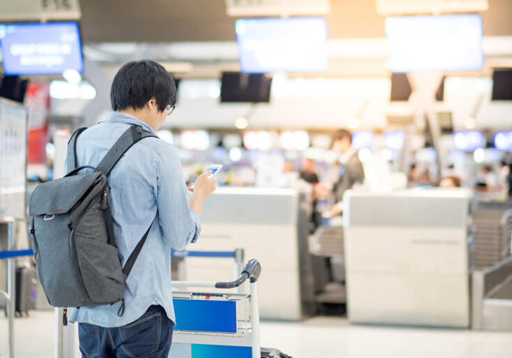 Young asian waiting for drop luggage at airline check-in counter in airport terminal - stock photo
