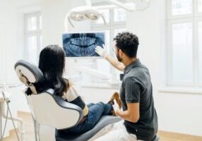 Dentist Showing Patient X-Ray Of Teeth After Check Up
