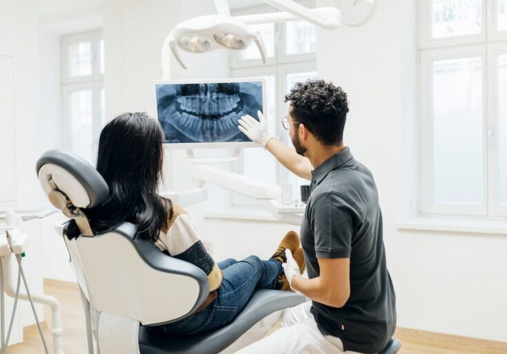Dentist Showing Patient X-Ray Of Teeth After Check Up