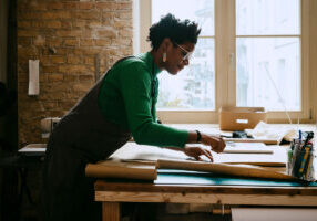 Female artist concentrating while doing craft at table in living room - stock photo