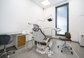 Dental clinic or practice, dental office interior with no people. Treatment room with dental chair, light, dental instruments.