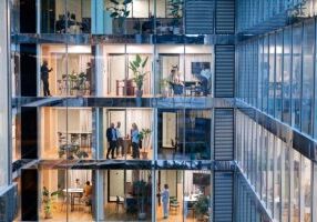 Businessmen and businesswomen working in several offices and on several floors in a modern building of a company - stock photo