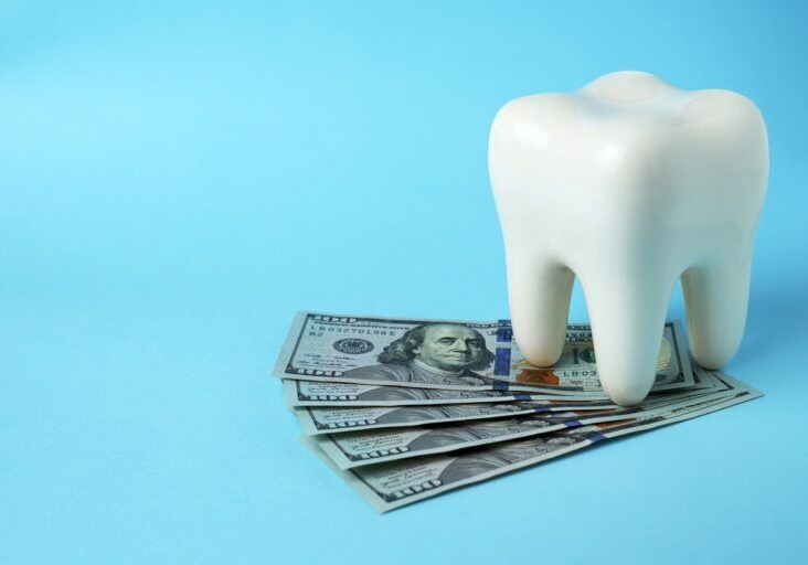 Dollar money bills and tooth model on a blue background with copy space