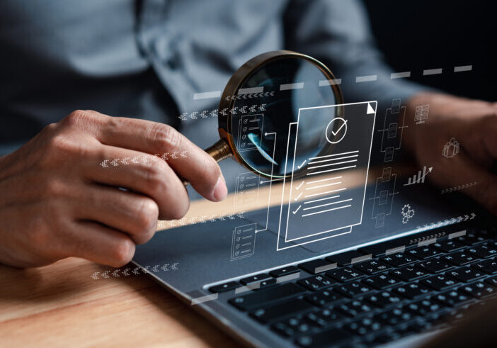 Data analysis concept stock photo - Man holding a magnifying glass over a laptop