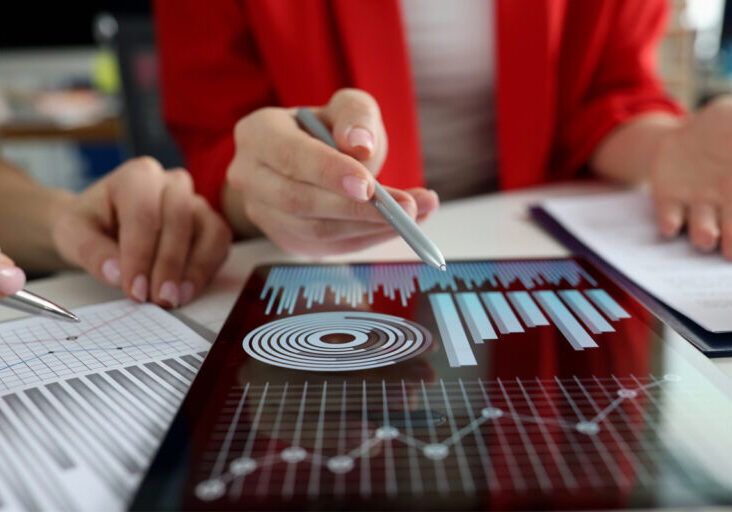 Business women studying charts and diagrams on digital tablet closeup