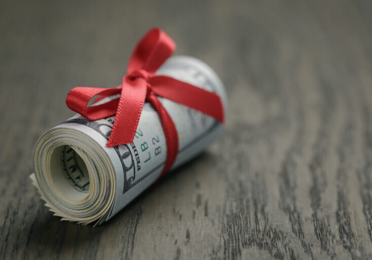 Roll of hundred dollar bills on wooden table